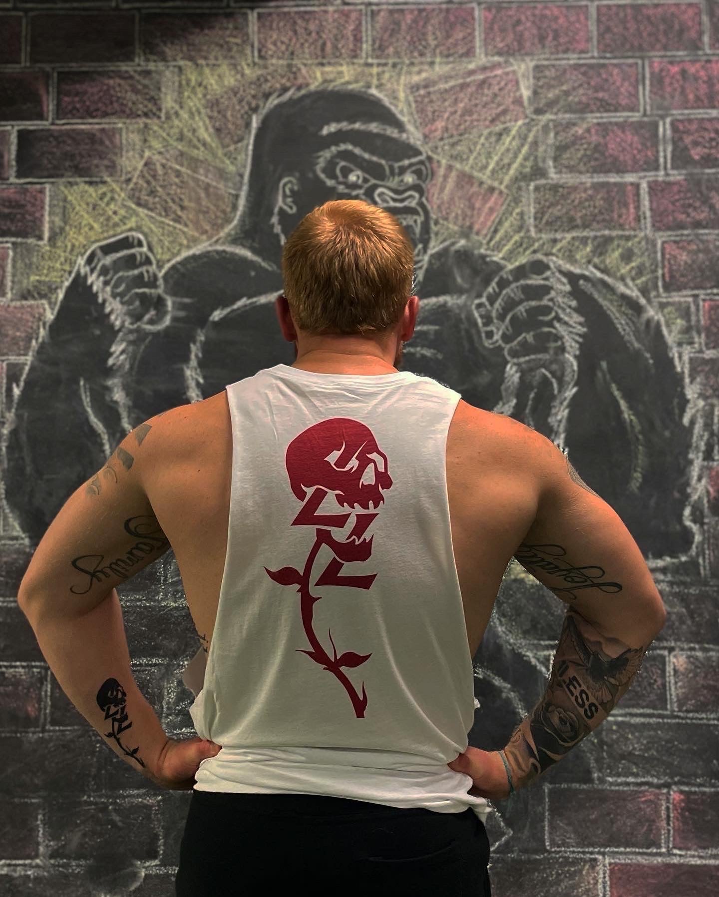 Back view of a person in a Lift To Live skull tank standing in front of a mural