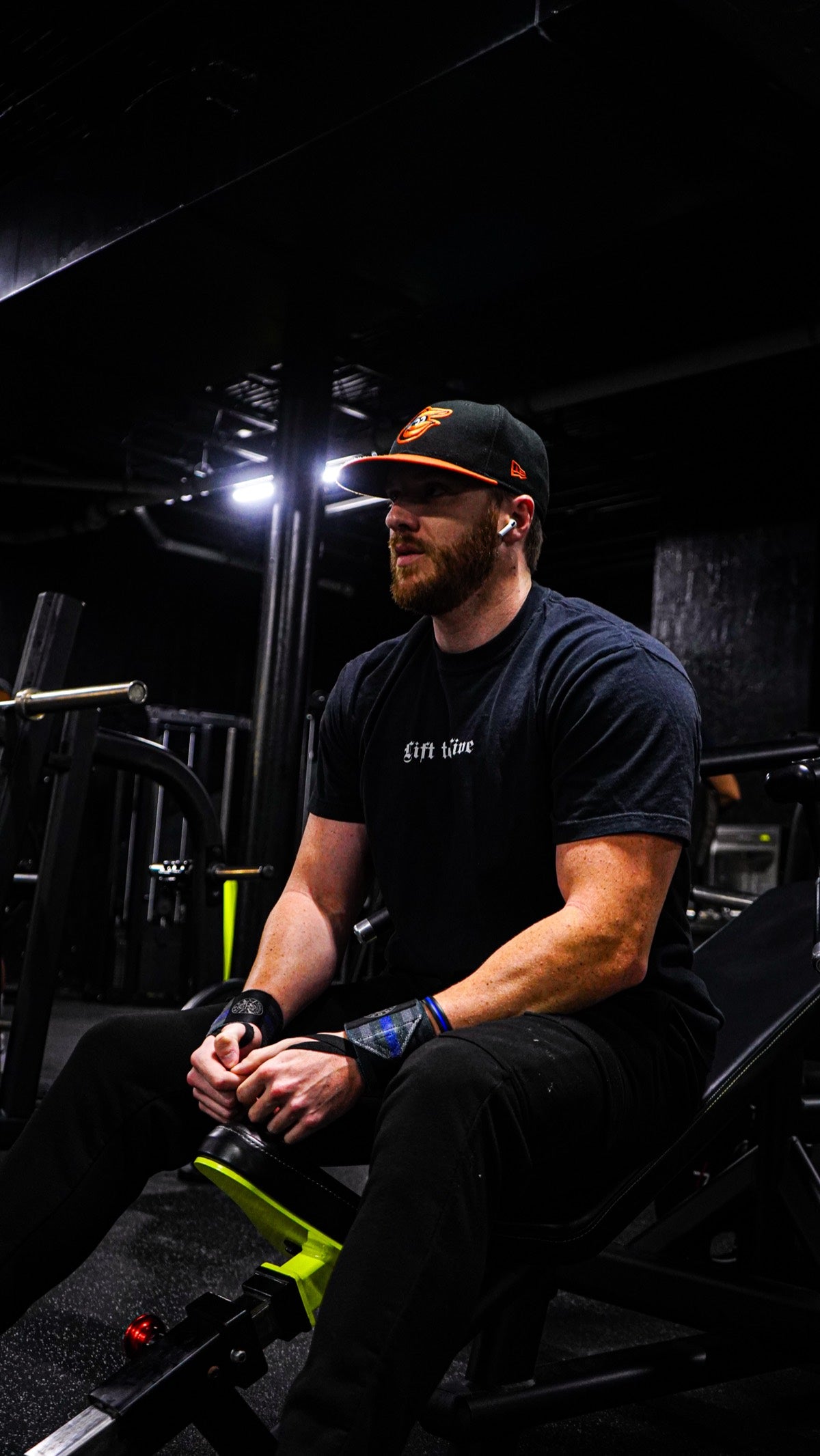 Lift To Live member seated in the gym, wearing a black tee